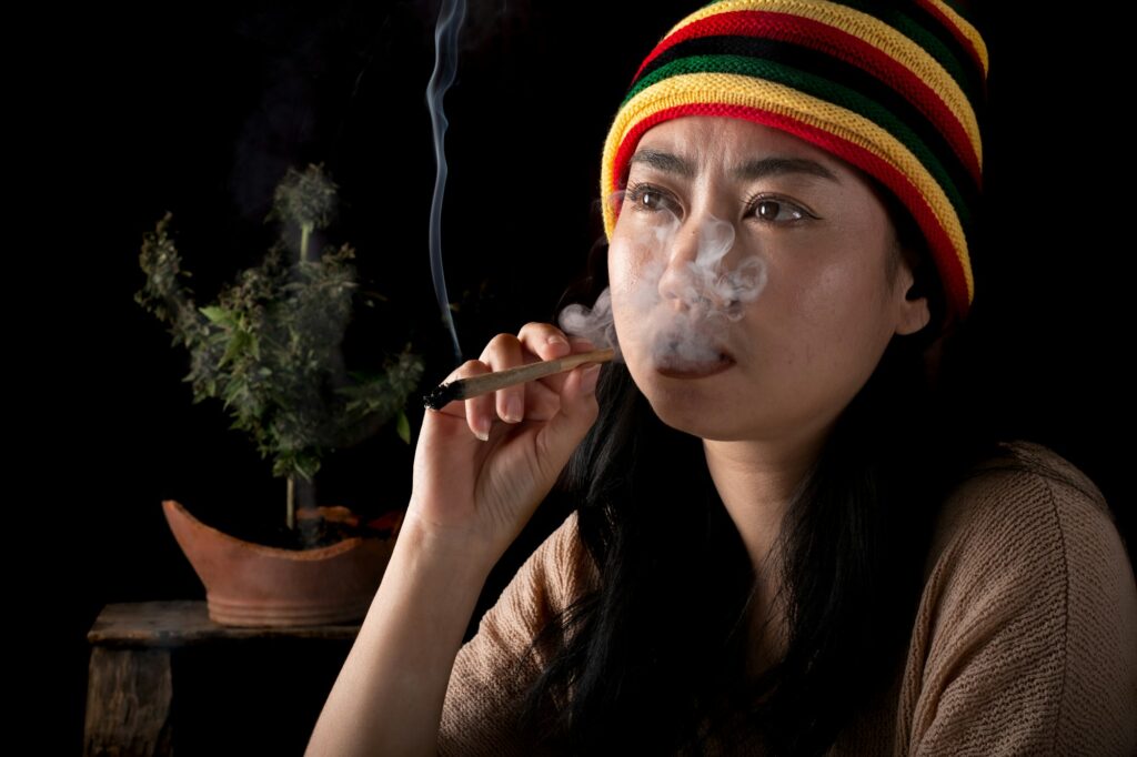 Beautiful Asia women smoking cigarettes at cannabis tree background