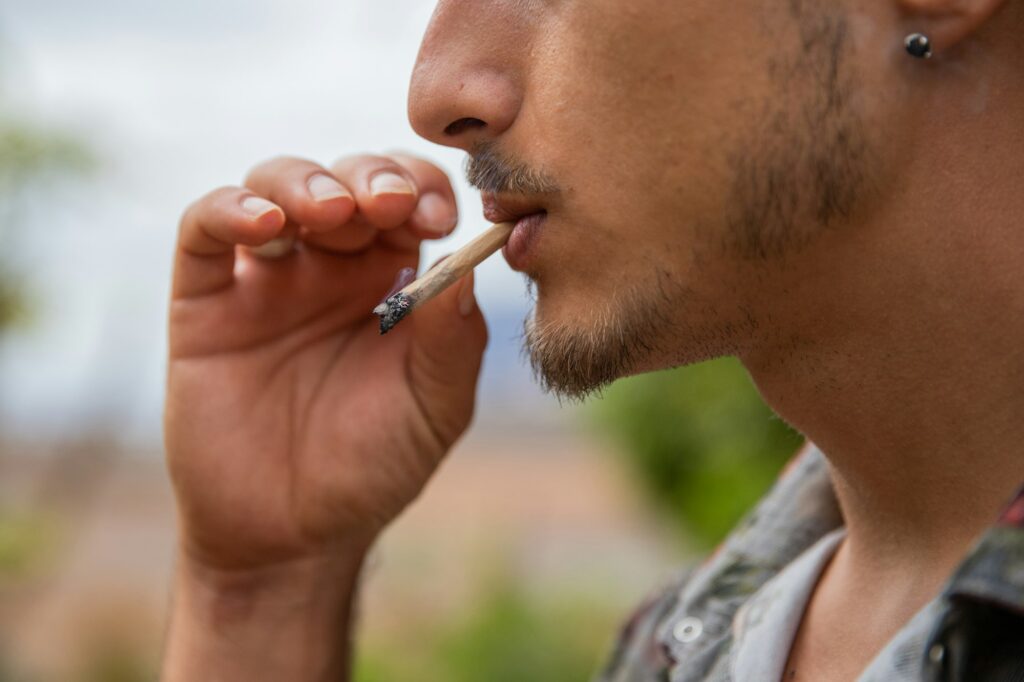 close up portrait of a man who smokes a joint of marijuana