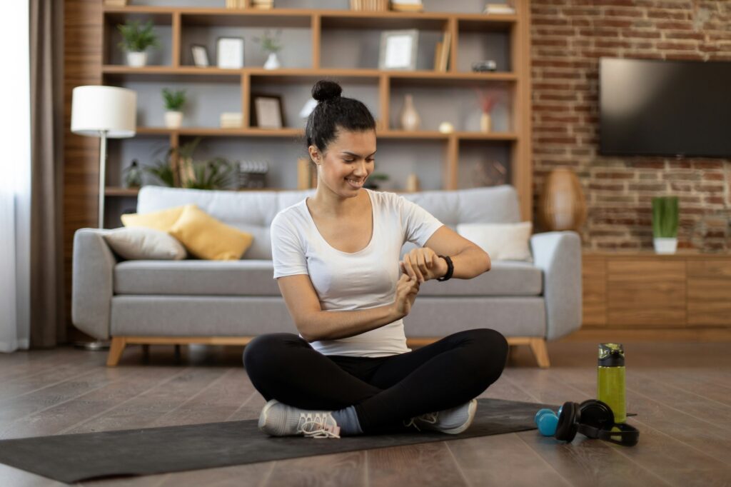 Woman monitoring workout achievements on smartwatch at home - Wellness Routine